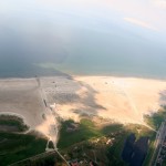 Luftaufnahme vom Ordinger Strand mit grünem Vorland, Sandstrand und Meer