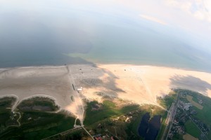Luftaufnahme vom Ordinger Strand mit grünem Vorland, Sandstrand und Meer